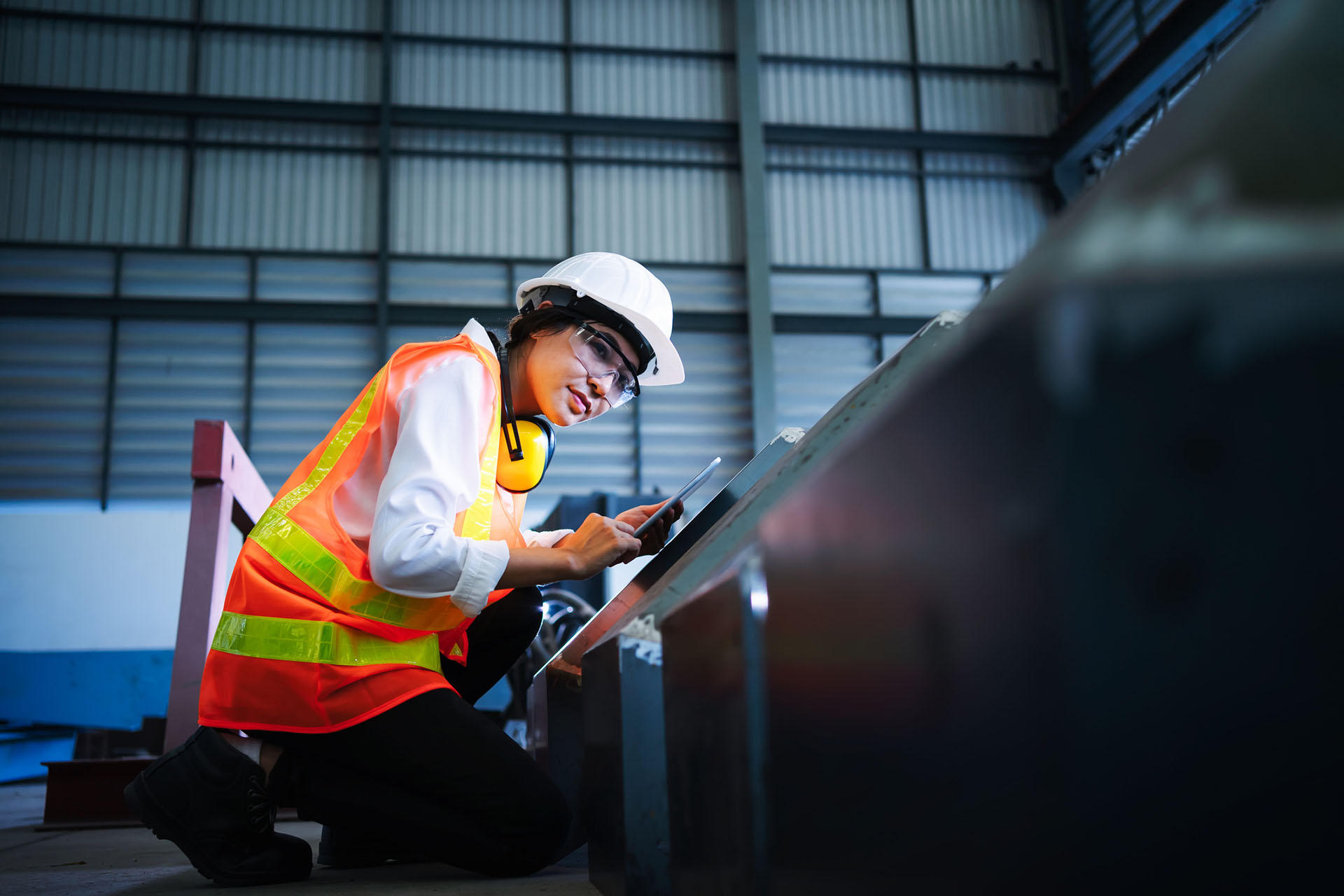 Une femme inspecte un équipement dans une usine