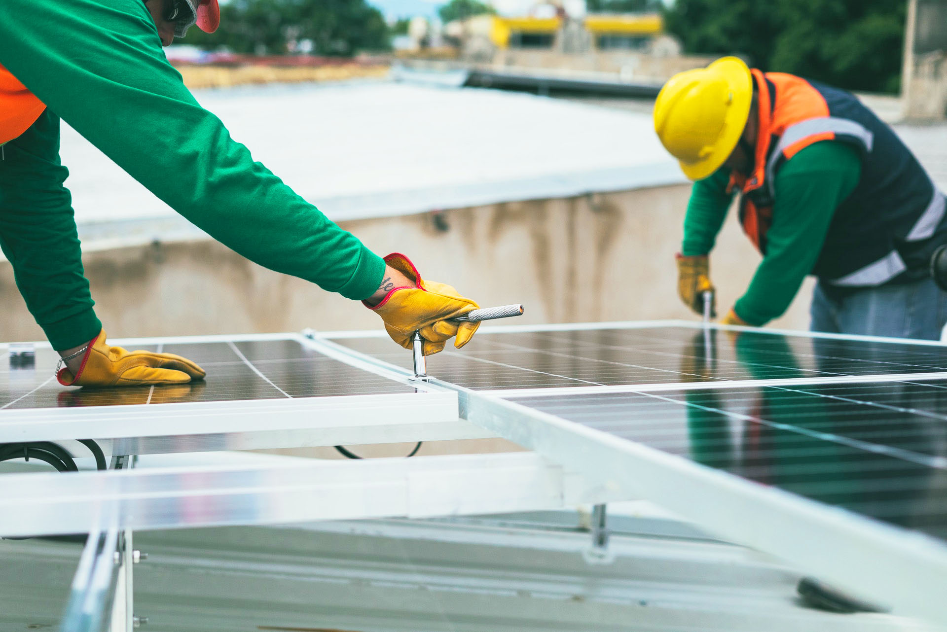 Deux personnes en vert installent un panneau photovoltaïque