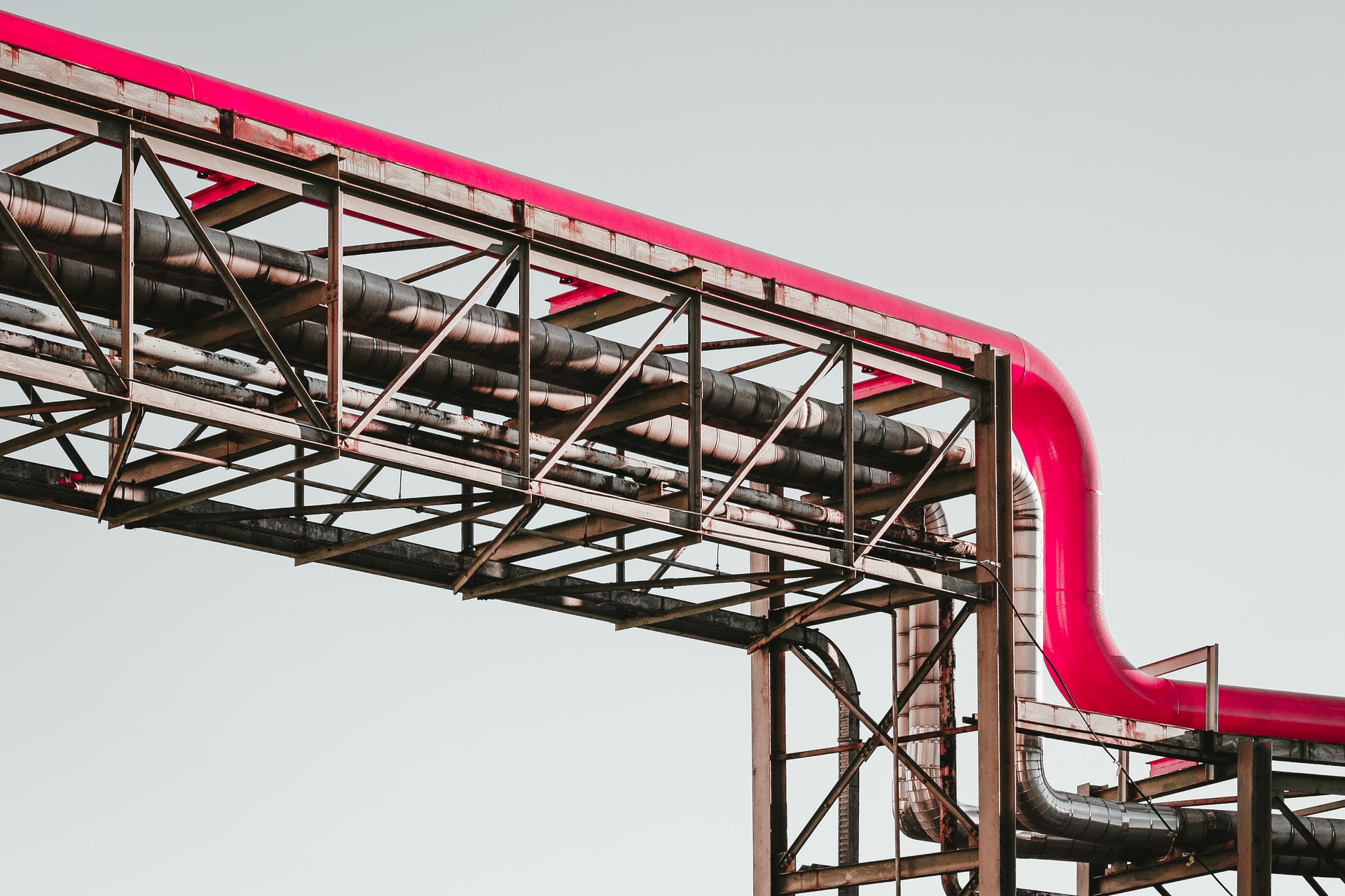 Vue de tuyaux roses et en métal gris à l'extérieur d'une usine