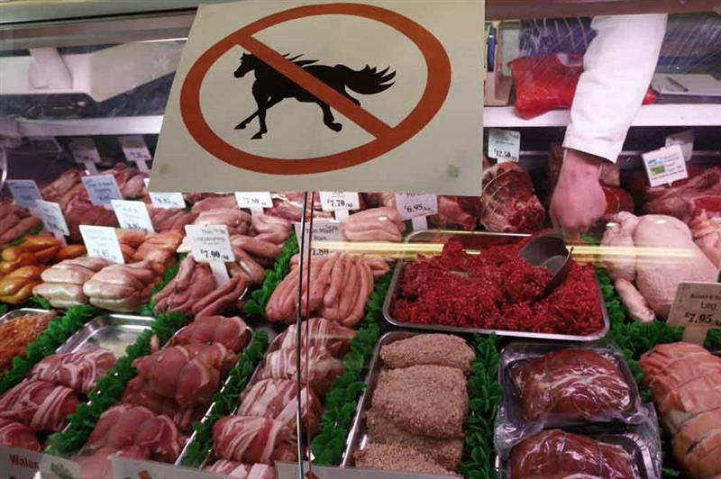 Vitrine de boucherie avec une affiche indiquant un cheval barré