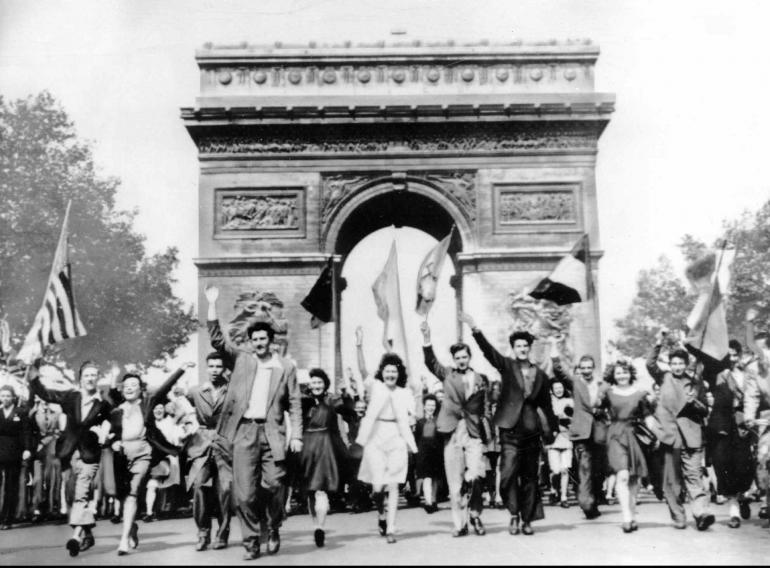 Hommes et femmes devant l'Arc de Triomphe brandissant des drapeaux français