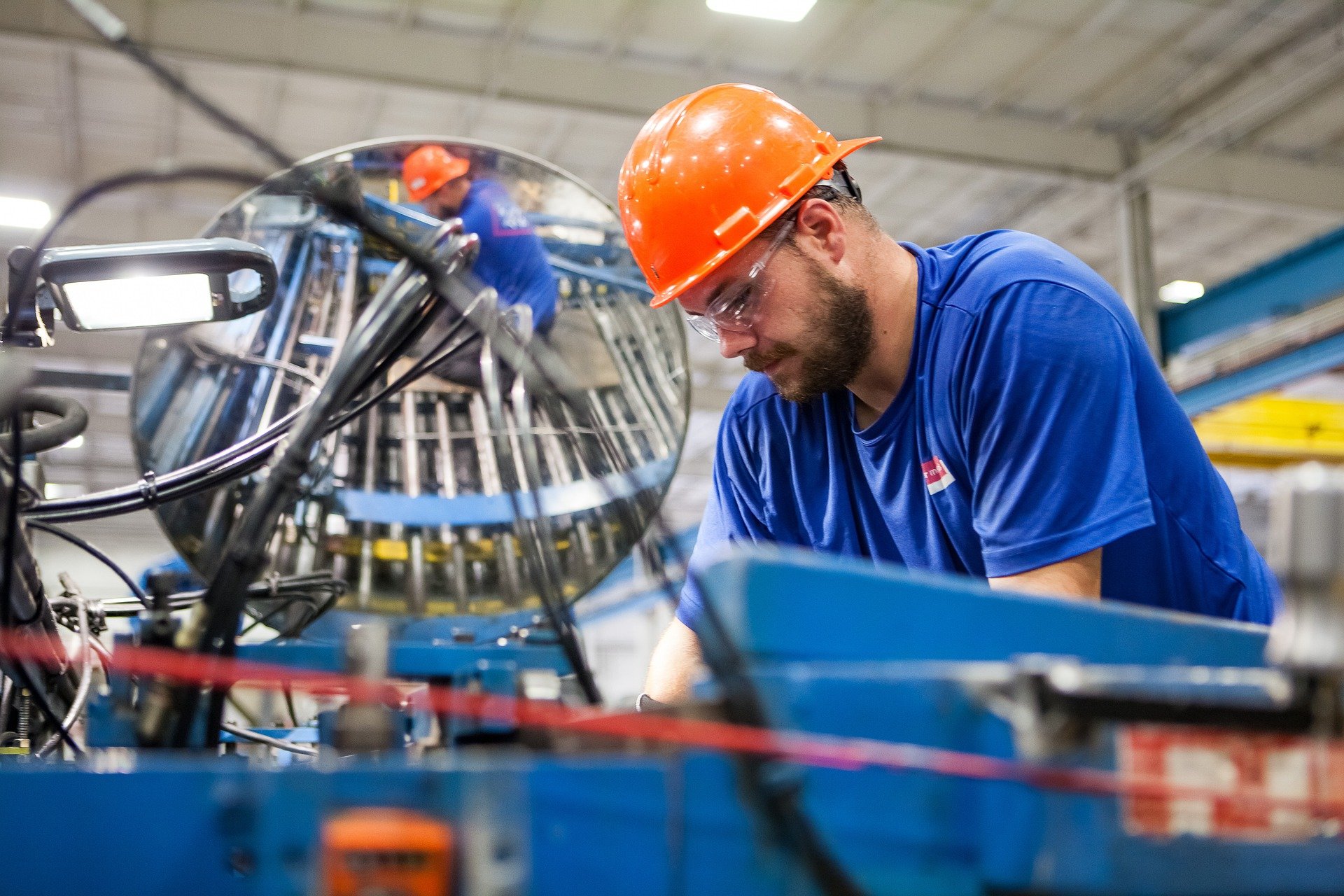 Dans une usine, un homme portant un casque de sécurité travaille sur une machine
