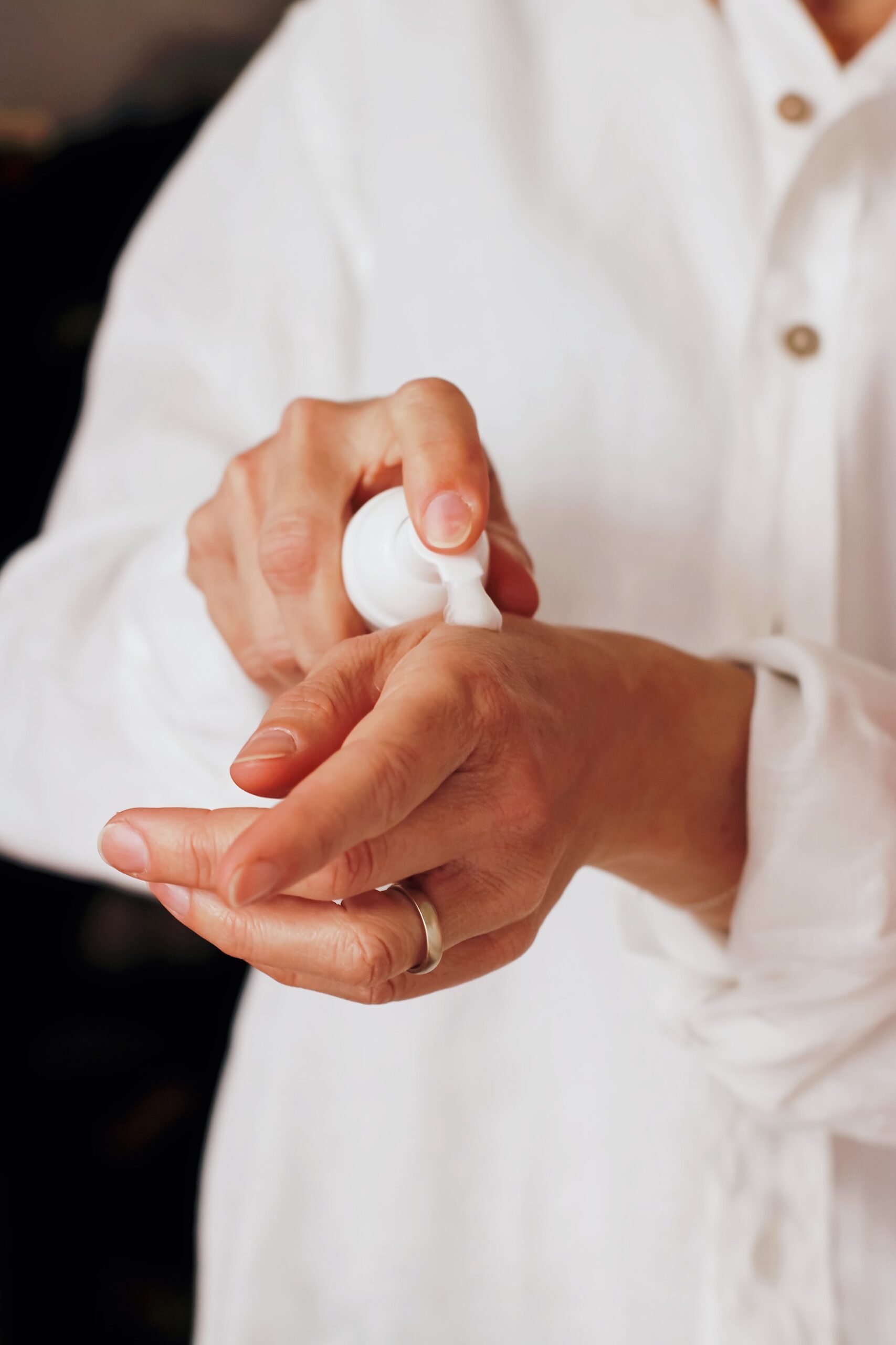 Gros plan sur les mains d'une personne blanche appuyant sur un flacon pompe sur sa main
