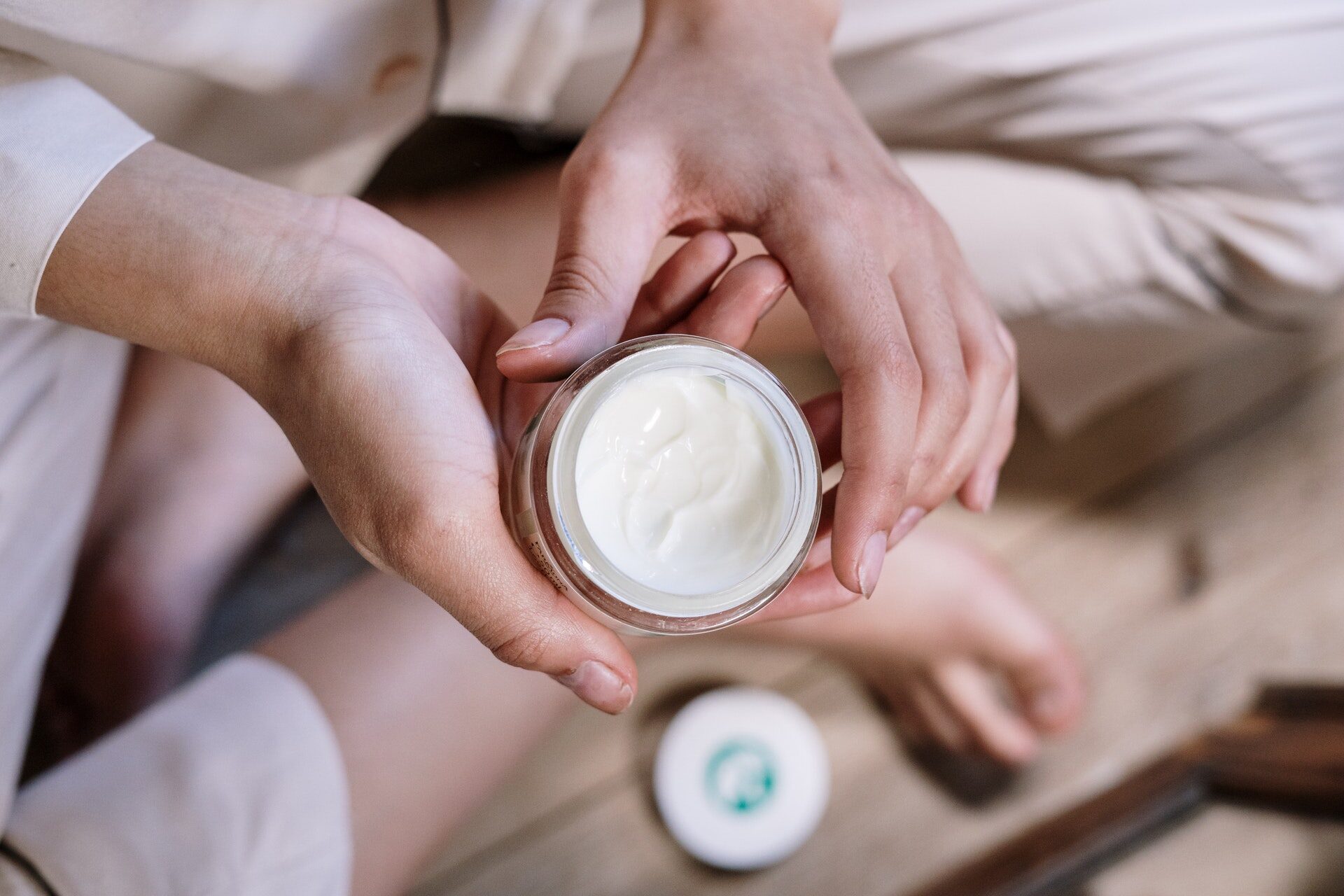 Gros plan sur des mains tenant un pot de crème pour le visage