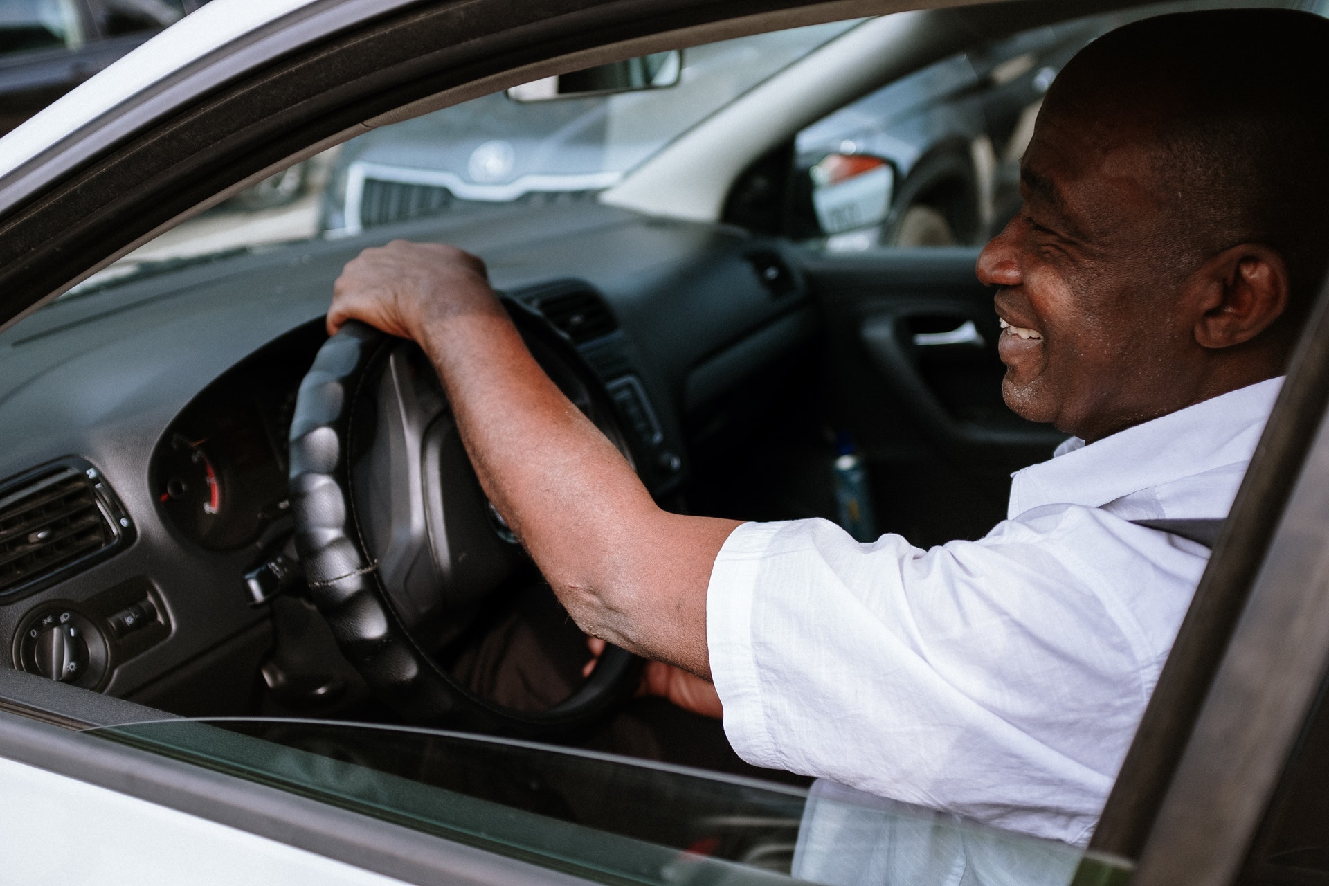 Un homme noir au volant d'une voiture grise souriant