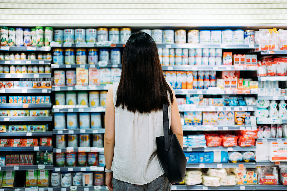 Vue de dos d'une femme brune devant un rayon de produits frais