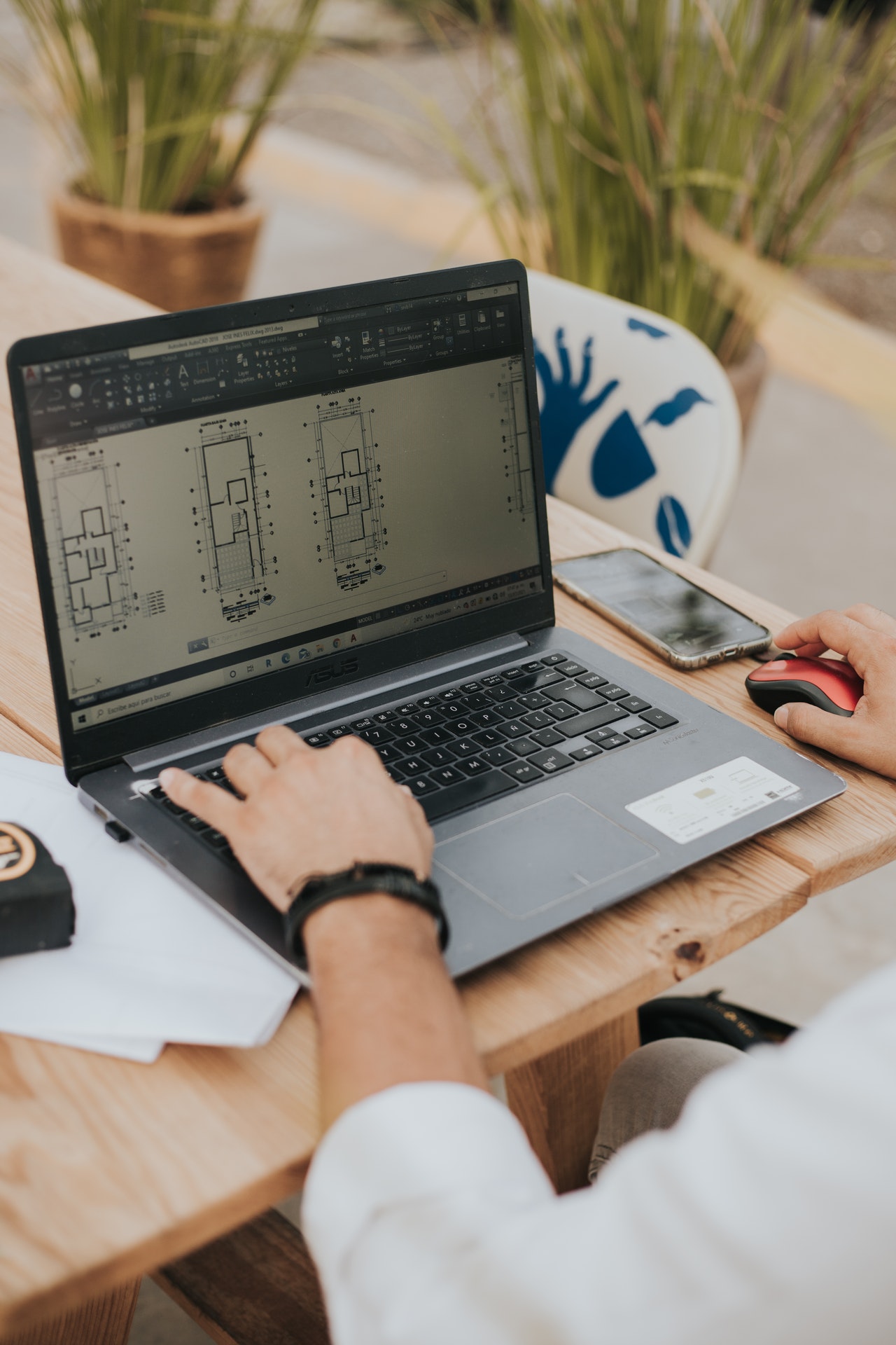 Gros plan sur les mains d'une personne travaillant sur des plans de bâtiment sur son ordinateur portable