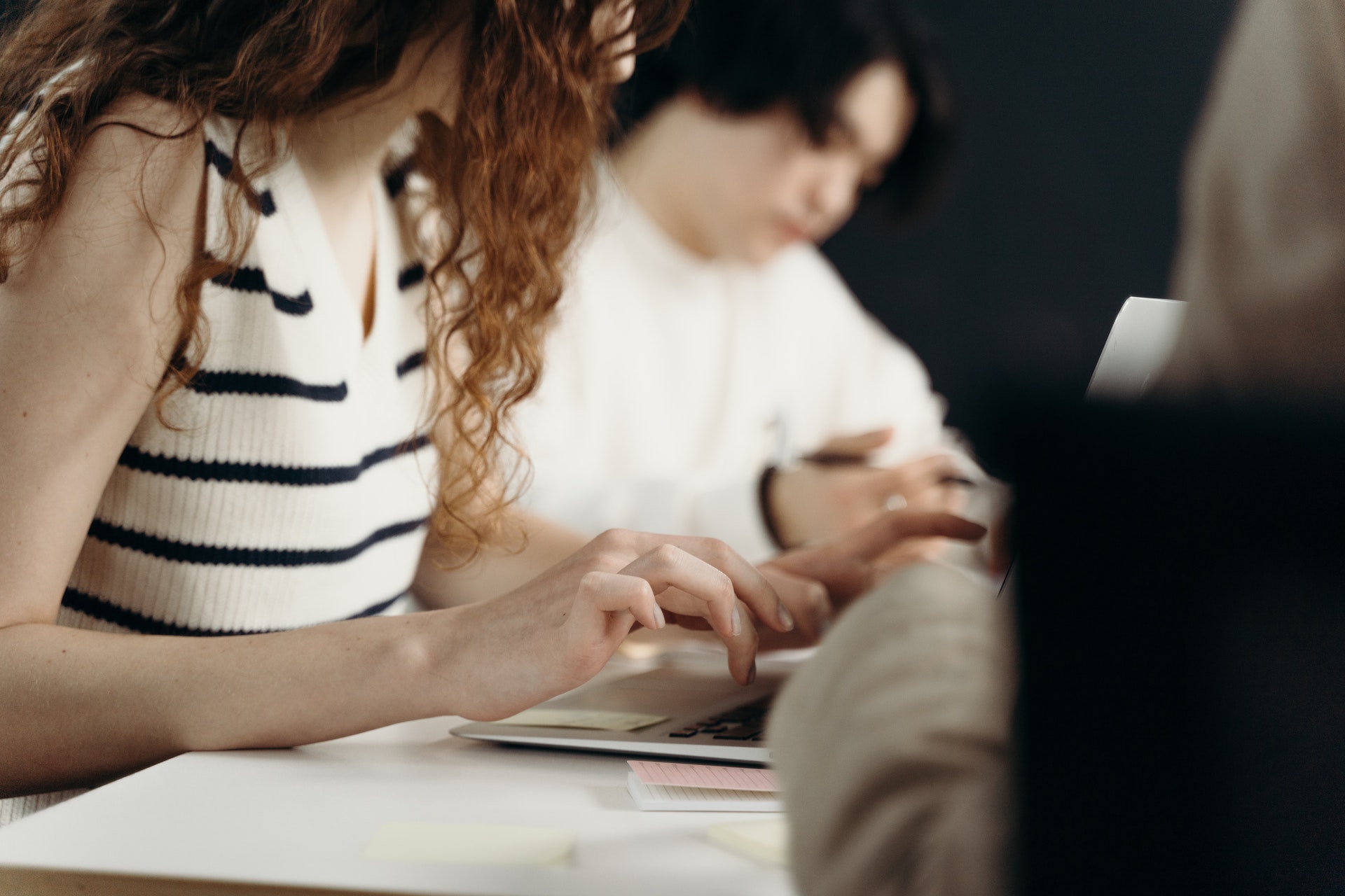 Gros plan sur les mains d'une femme rousse au-dessus d'un clavier d'ordinateur portable