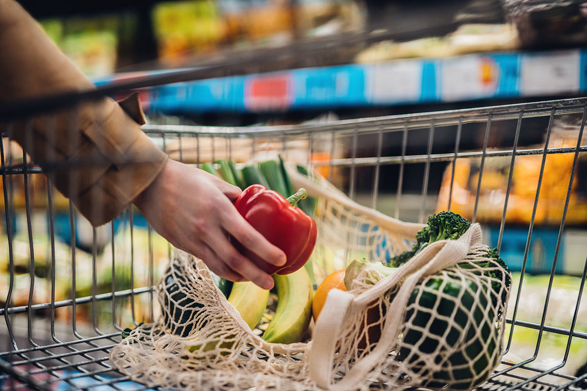 Main d'une personne blanche posant un poivron dans un panier