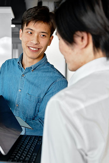 Un homme asiatique debout sourit à une personne à côté de lui