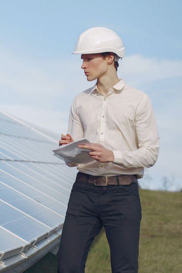 Un homme blanc face à des panneaux photovoltaïques prend des notes