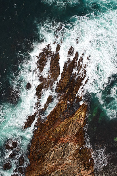 Vue en plongée de rochers dans la mer écumante