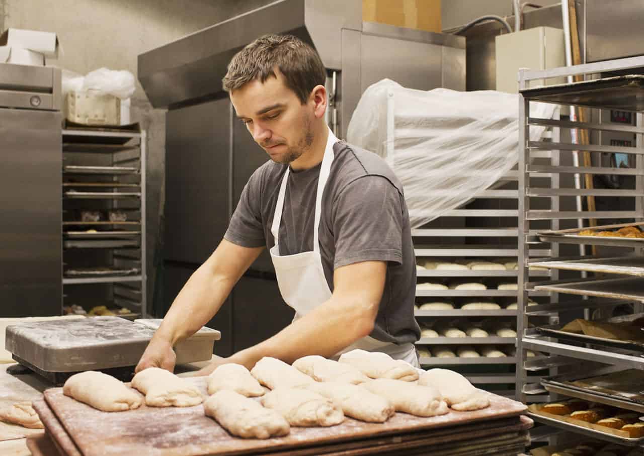 Un jeune boulanger blanc façonne des pains