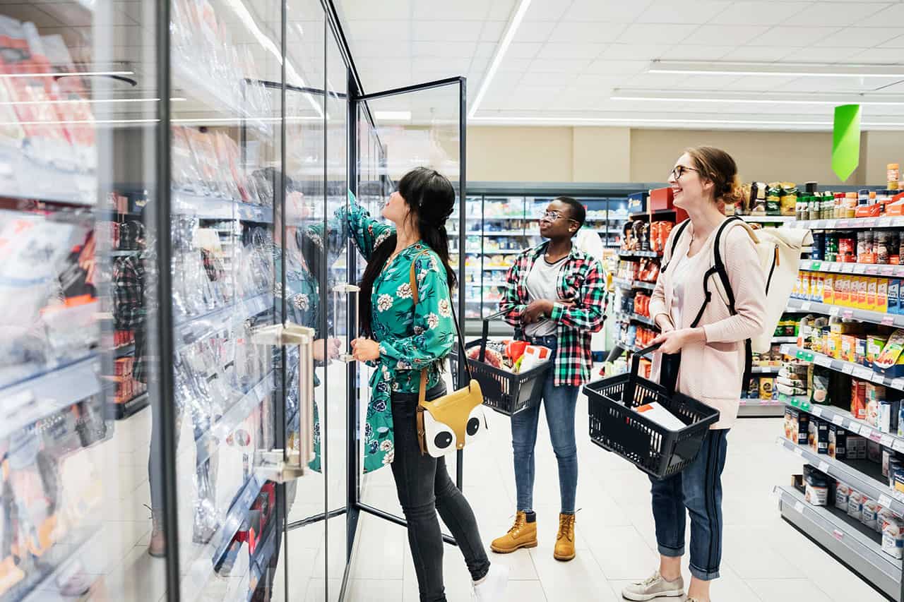 Trois femmes devant une armoire frigorifique dans un supermarché