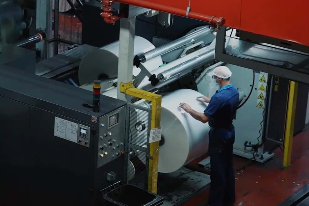 Une personne debout près d'une machine dans une usine plasturgique