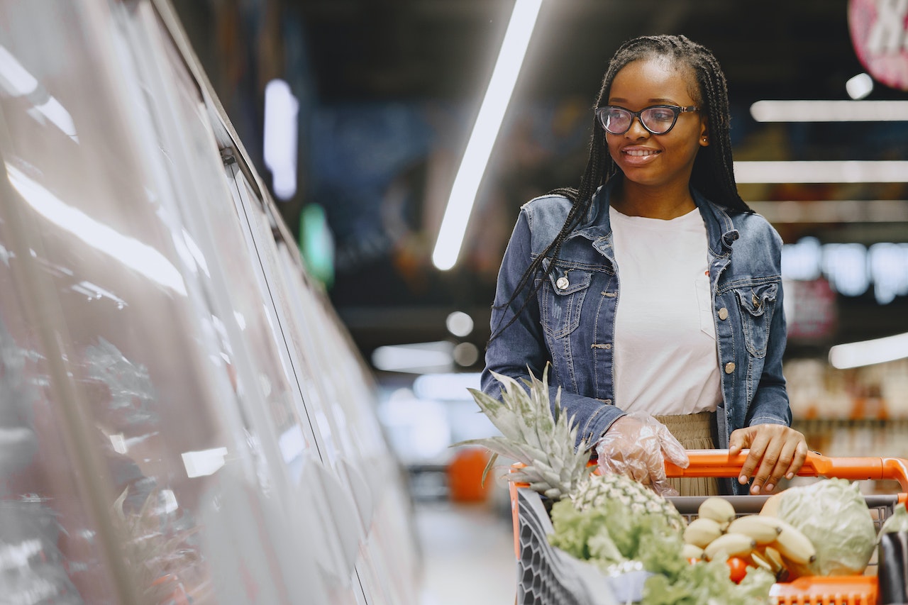Femme noire poussant un chariot de courses dans un supermarché