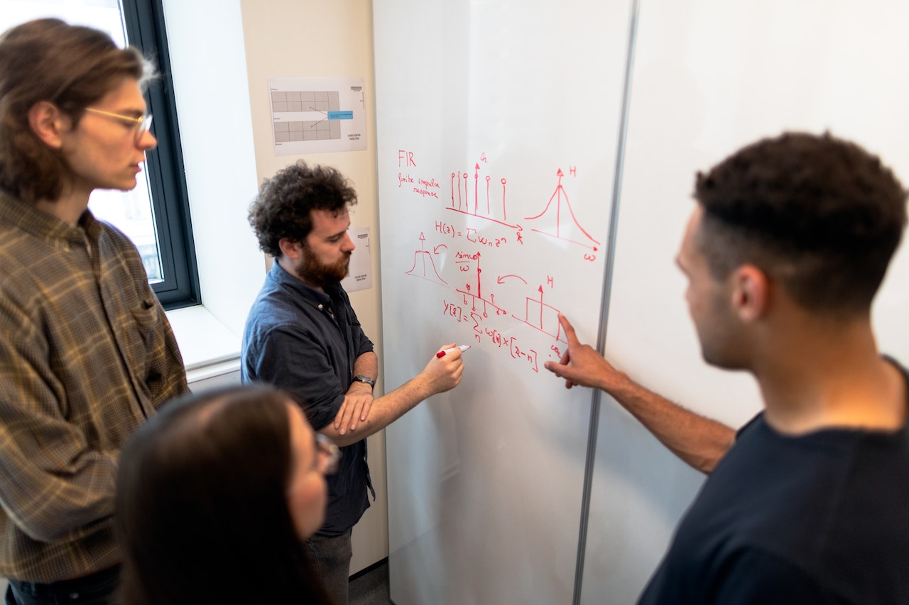 4 personnes devant un tableau blanc comportant des formules mathématiques