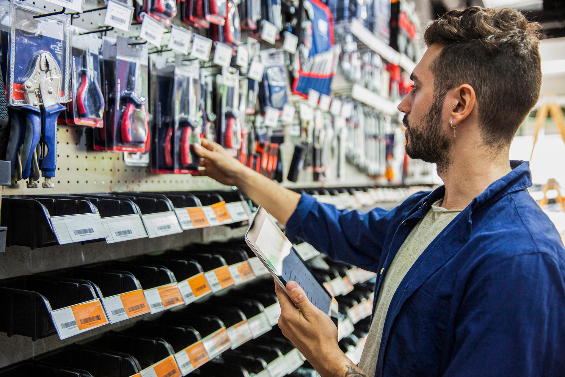 Homme blanc dans un magasin de bricolage prenant un tournevis dans les rayons