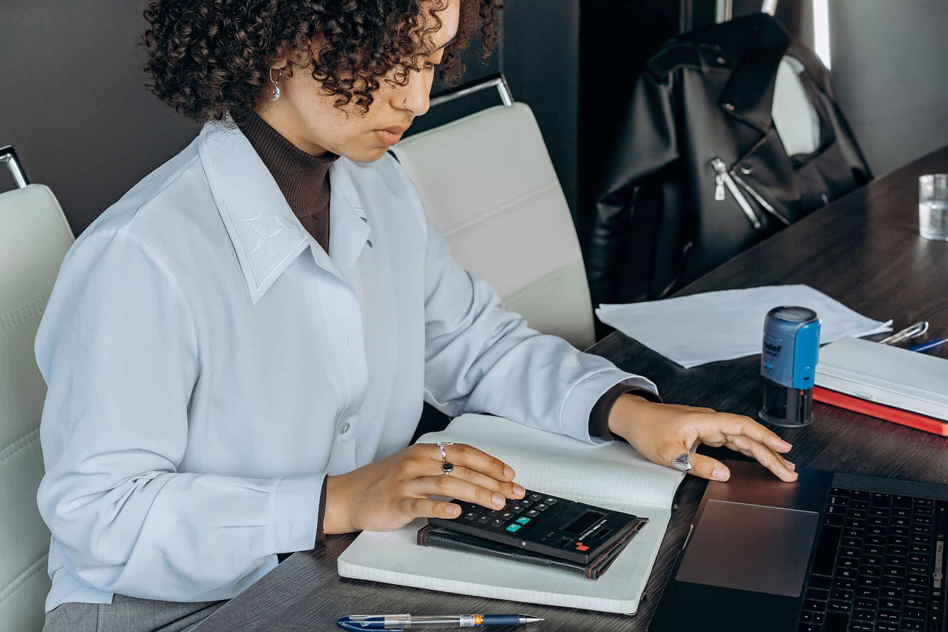 Femme à la peau mate tapant sur une calculatrice