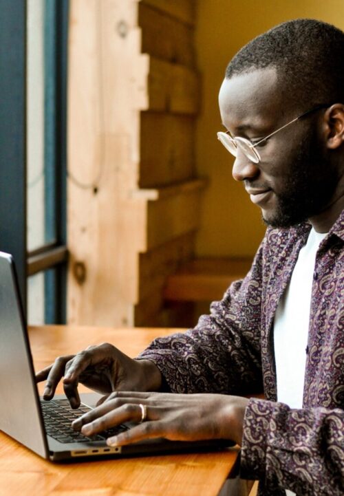Homme noir assis devant un ordinateur portable