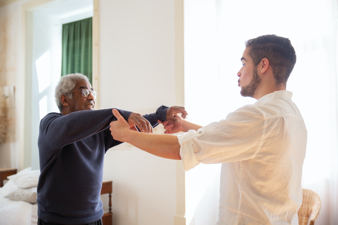 Un homme noir senior fait des exercices de kiné face à un soignant blanc