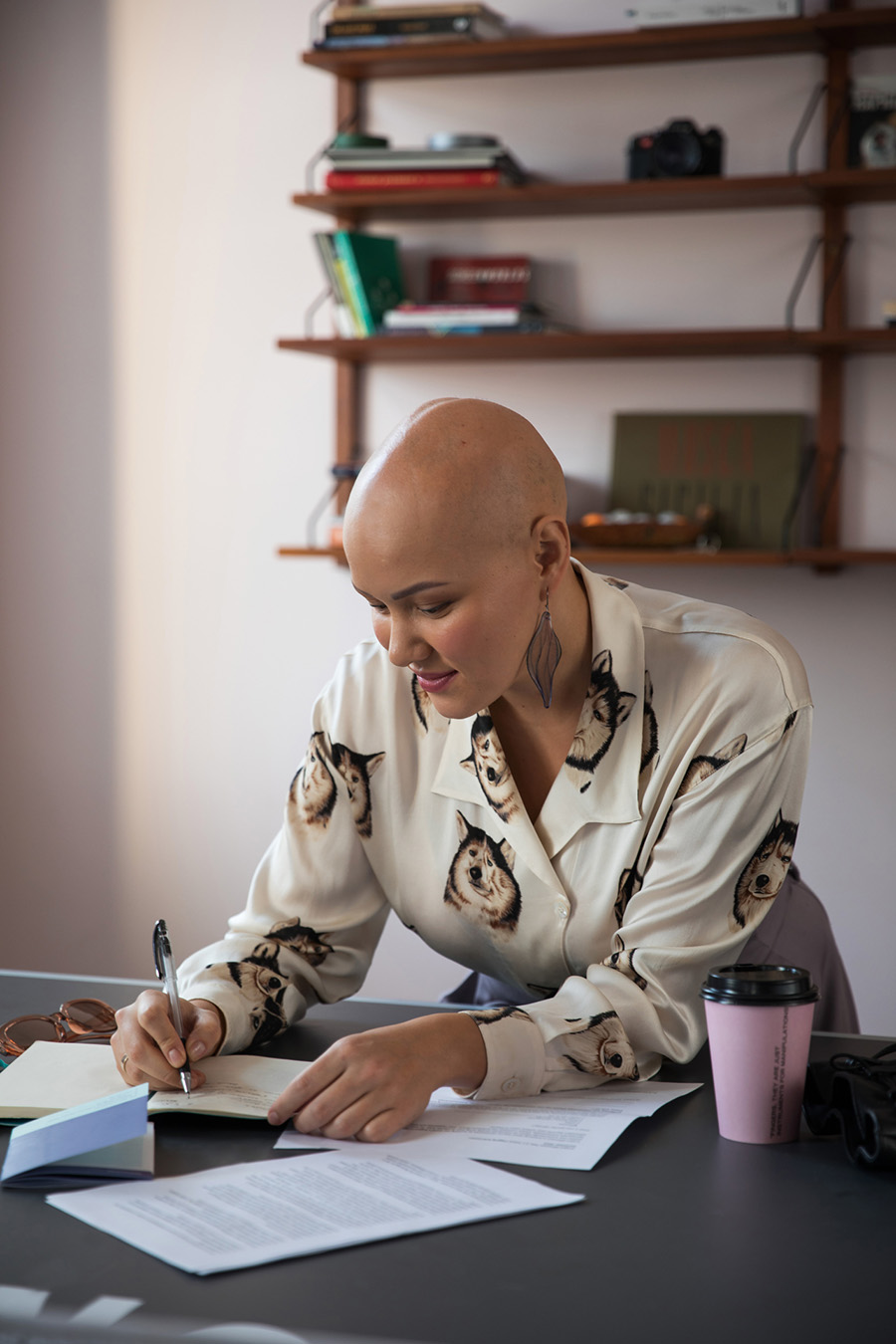 Femme blanche chauve debout écrivant à un bureau