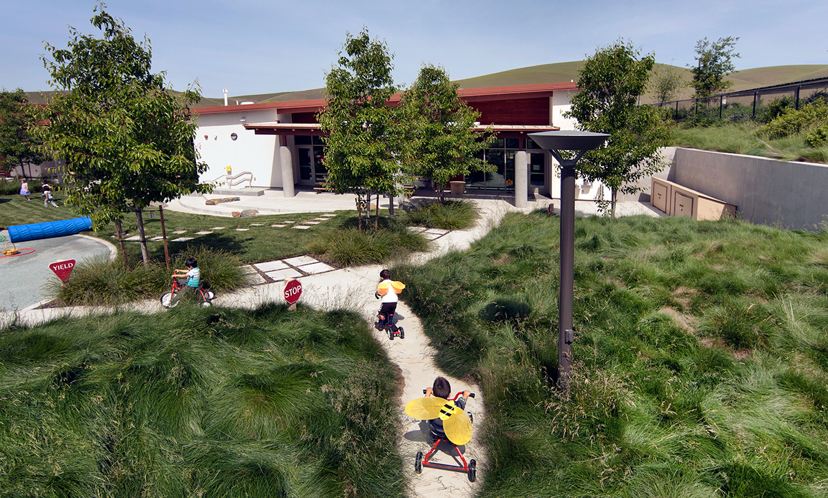 Enfants faisant du tricycle dans une cour d'école végétalisée