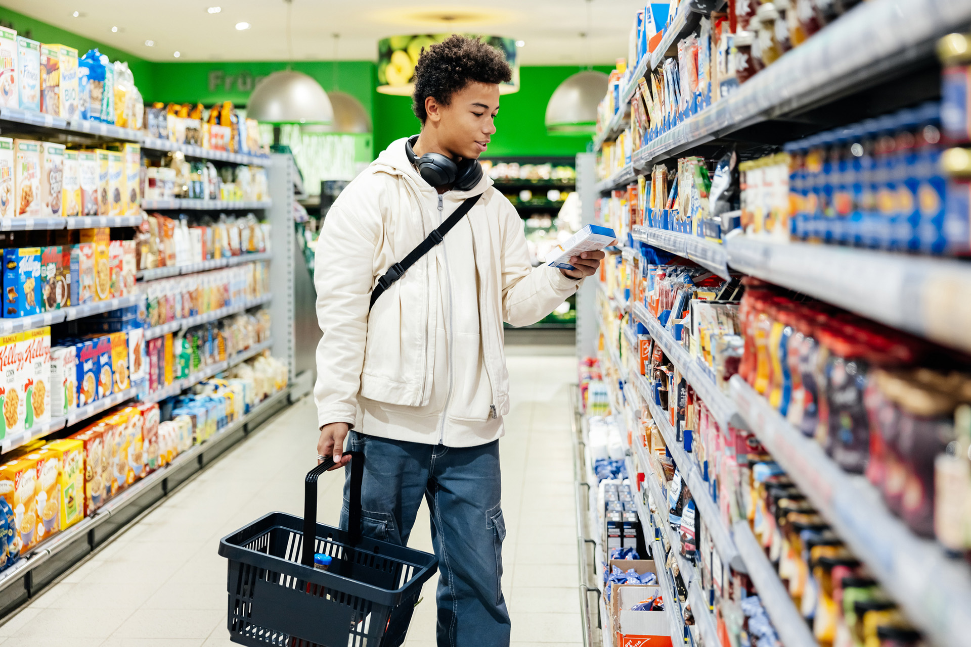 Un jeune homme noir lit l'étiquette d'un produit dans un rayon de supermarché