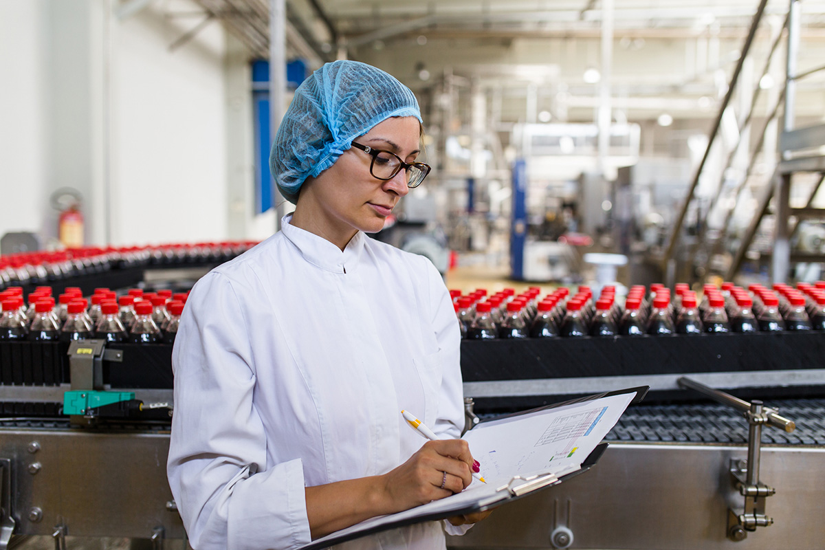 Femme blanche écrivant sur un document dans une usine d'embouteillage